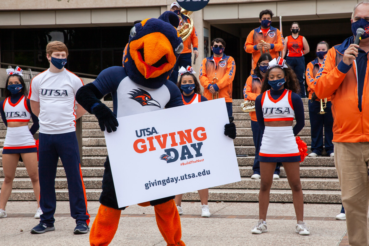 Rowdy holding giving days sign with cheerleading team